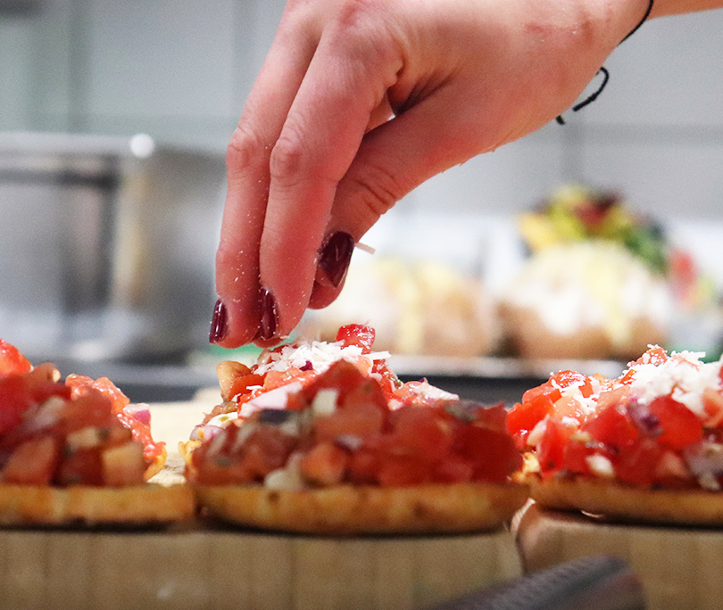 Cateraar die Italiaanse bruschetta opmaakt, perfect voor Italiaanse catering